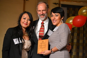Two women and a man receiving an award